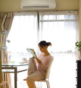 Woman reading comfortably under an AC unit