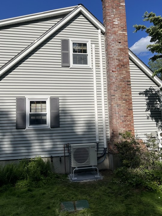 Mitsubishi heat pump outdoor unit installed beside a Merrimack NH home